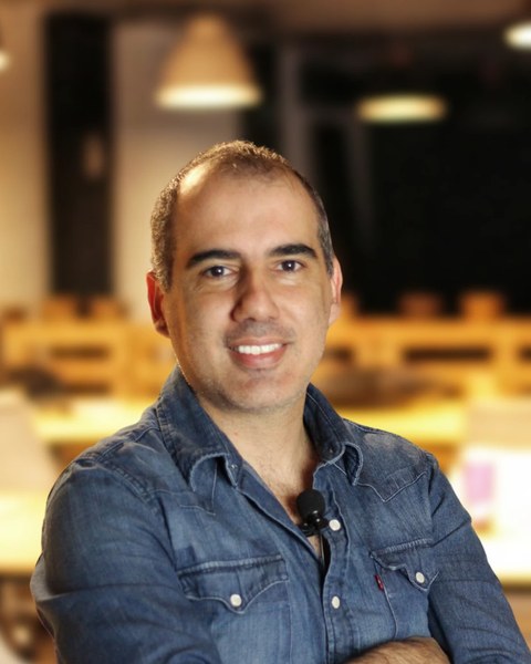 Roberto Calderon sorrindo, de camisa jeans, no coworking